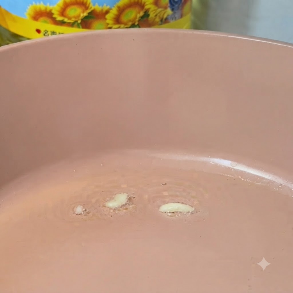 Gehackter Knoblauch bräst in einer heißen rosa Pfanne mit Öl.