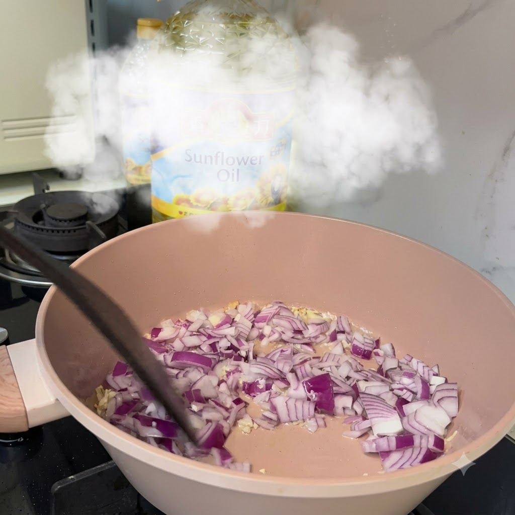 Gewürfelte rote Zwiebeln kochen in einer Pfanne mit Knoblauch und Öl über einem Herd.