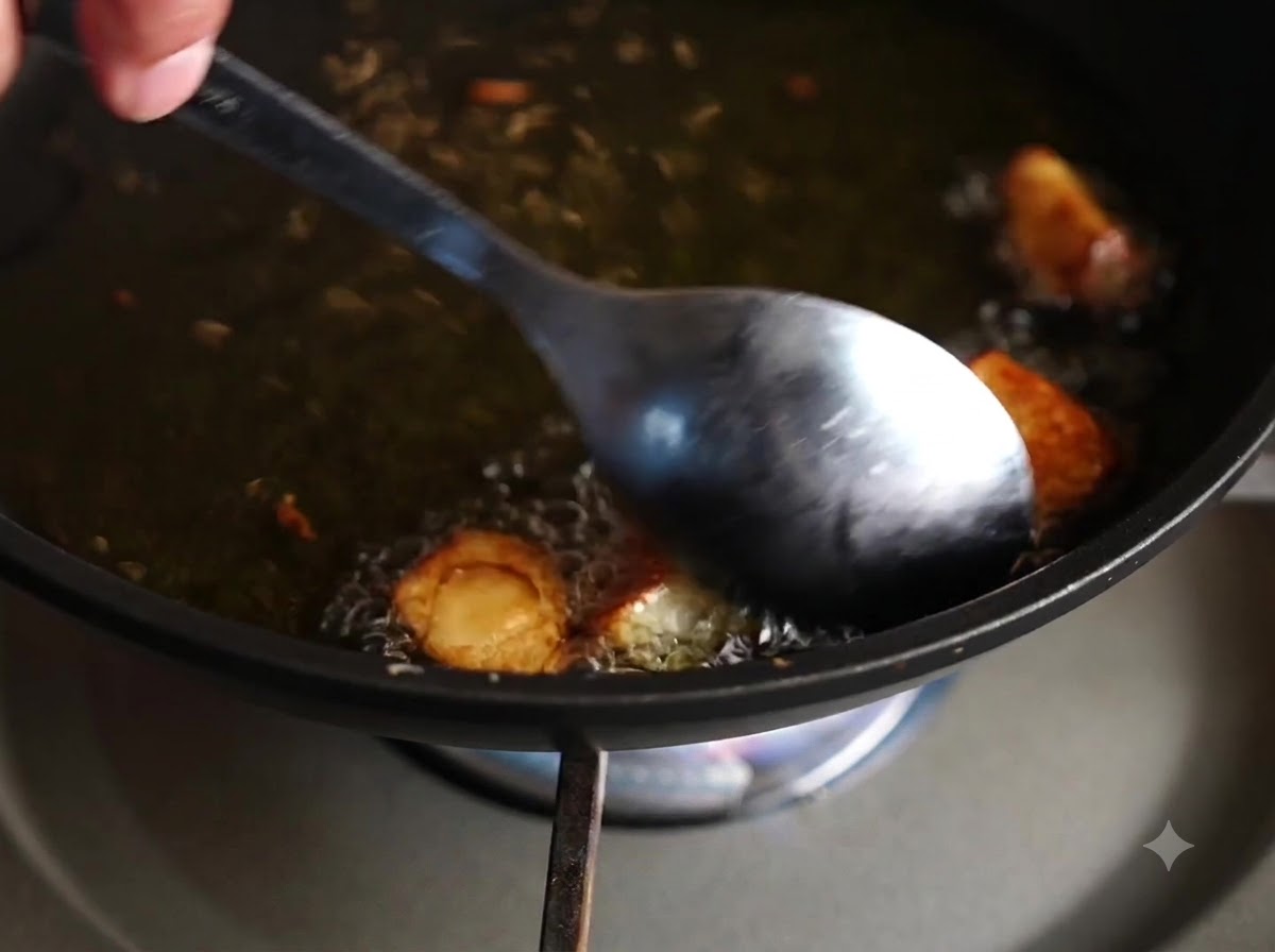 Ein Löffel rührt und wendet Knoblauchzehen, die in heißem Öl braten.