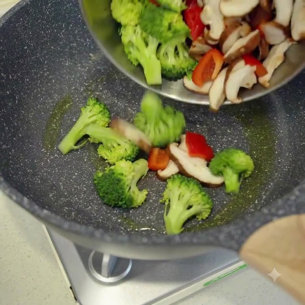 Frisch geschnittenes Gemüse wird aus einer Schüssel in einen heißen, geölten Wok gegeben.