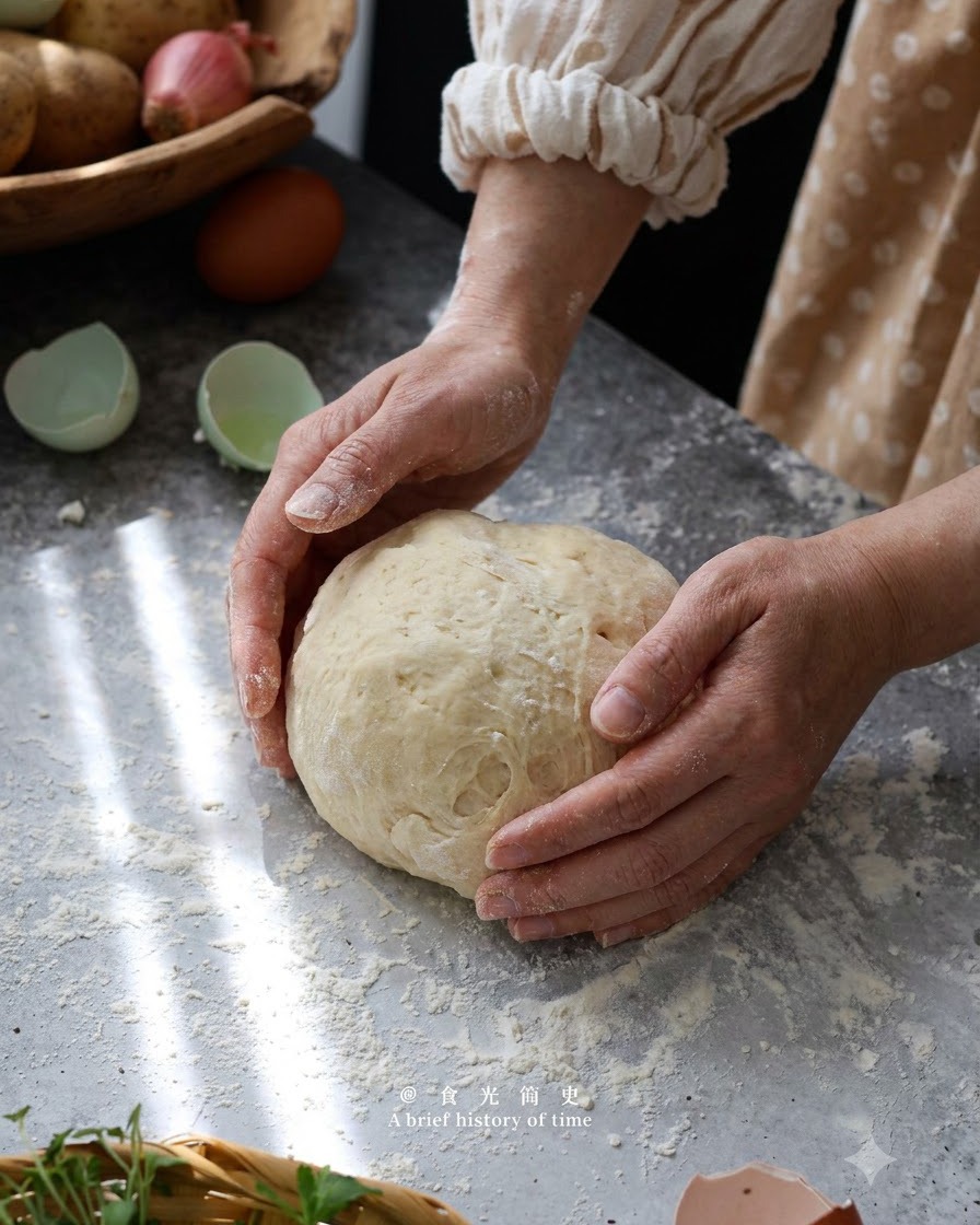 Hände formen und kneten sanft Gnocchiteig zu einer Kugel auf einer bemehlten Oberfläche.