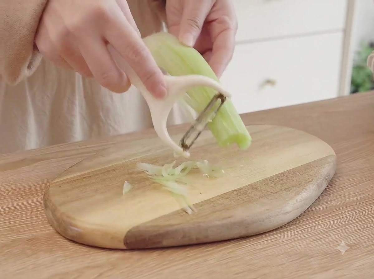 Sellerie, Karotten und Zwiebeln werden auf einem Holzschneidebrett in kleine Stücke fein gewürfelt.