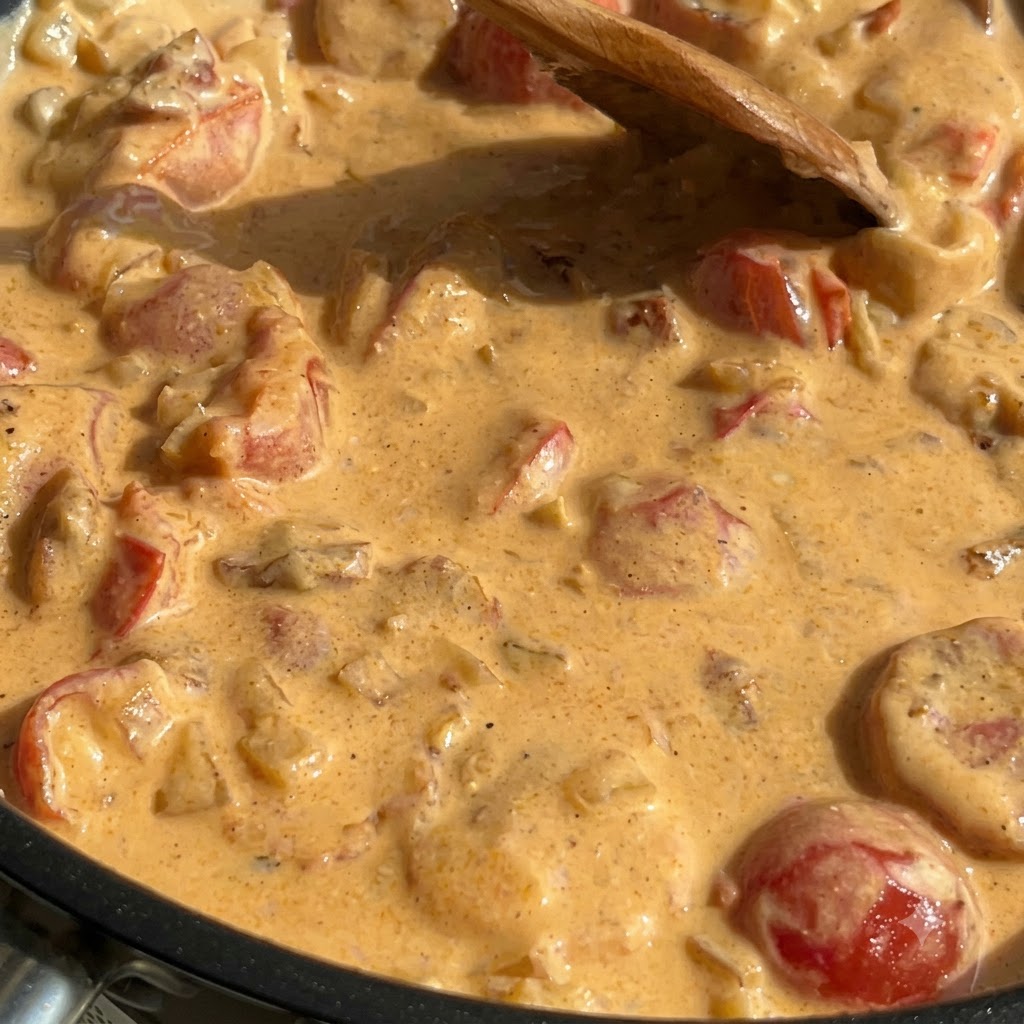 Gekochte Pasta, Spinat und Lachs sind in einer dicken cremigen Sauce in einer Pfanne vermischt.