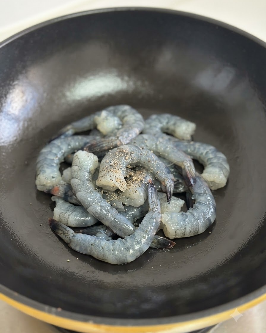Mit schwarzem Pfeffer gewürzte rohe Garnelen werden in einem schwarzen Wok angebraten.