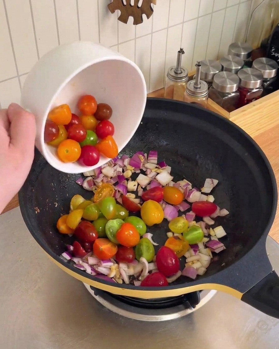 Gehackte rote Zwiebel und Knoblauch werden in einem schwarzen Wok geschwenkt und angebraten.