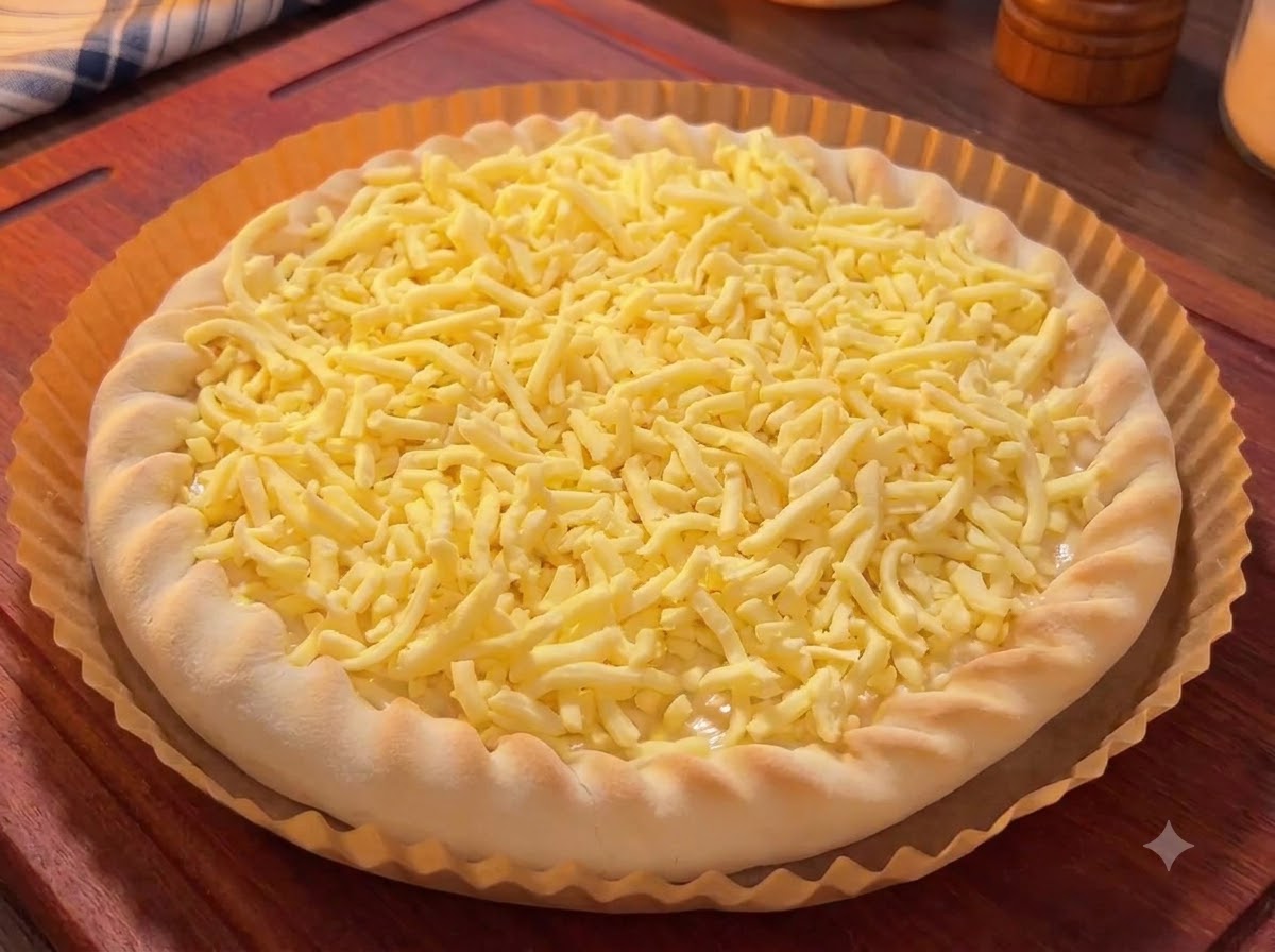 Ein mit Käse bedeckter Pizzaboden, garniert mit bunten Mangostücken, Drachenfruchtstücken und Kirschen.