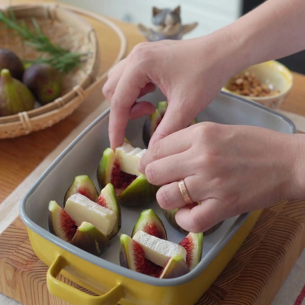 Eine Hand legt ein Stück weißen Brie-Käse in die geöffnete Mitte einer kreuzweise geschnittenen Feige.