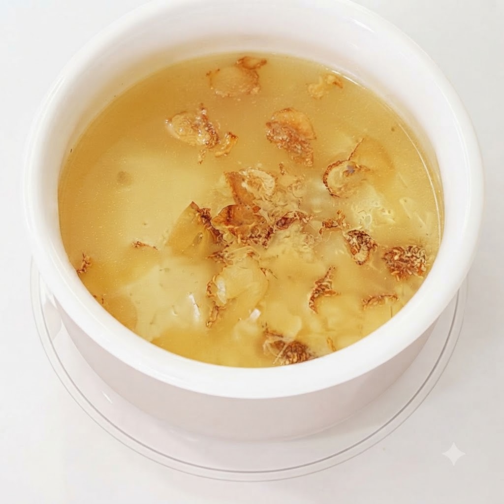 Knoblauchschalen und -zehen kochen im Wasser, um eine Brühe zu bilden.