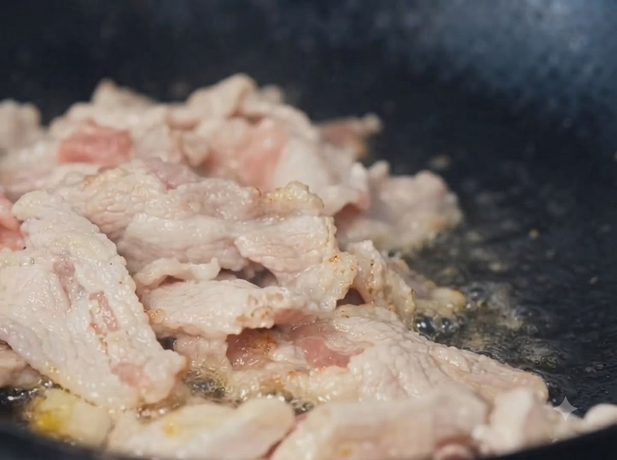 In Streifen geschnittenes Schweinefleisch brät in einem Wok.