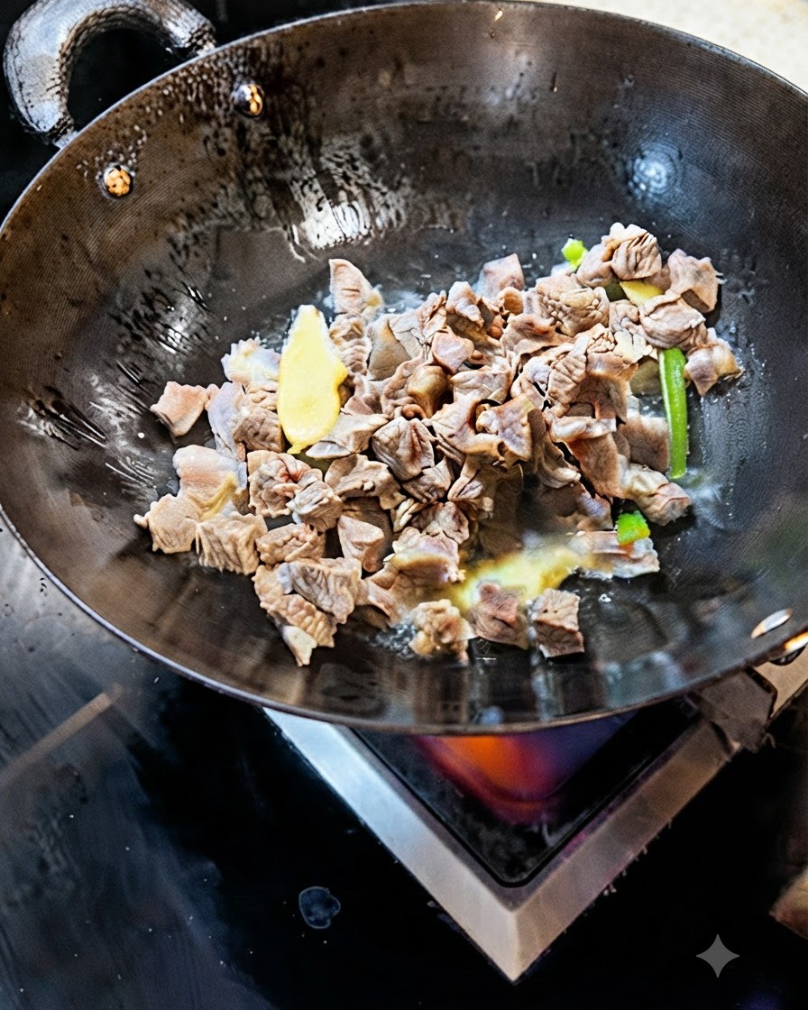 Blanchierte Rindfleischwürfel braten zusammen mit Ingwer- und Frühlingszwiebelscheiben in einem Wok an.