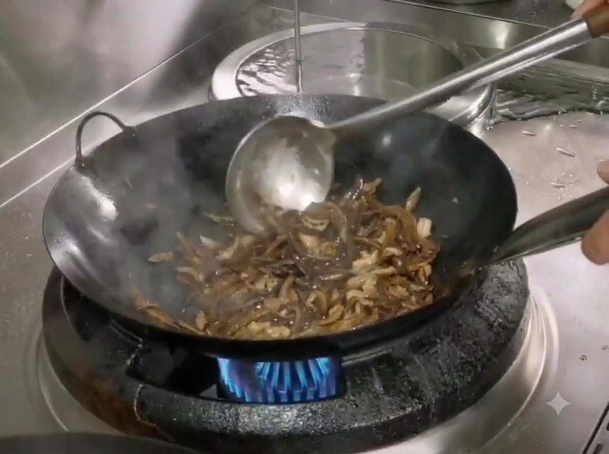 Salz und Zucker werden mit einem Metallspatel in den Wok mit Bambussprossen und Schweinefleisch eingerührt.
