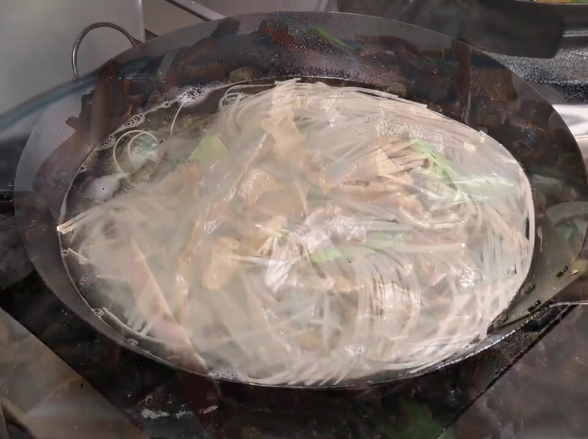 Nudeln kochen heftig in einem großen, mit Wasser gefüllten Wok.