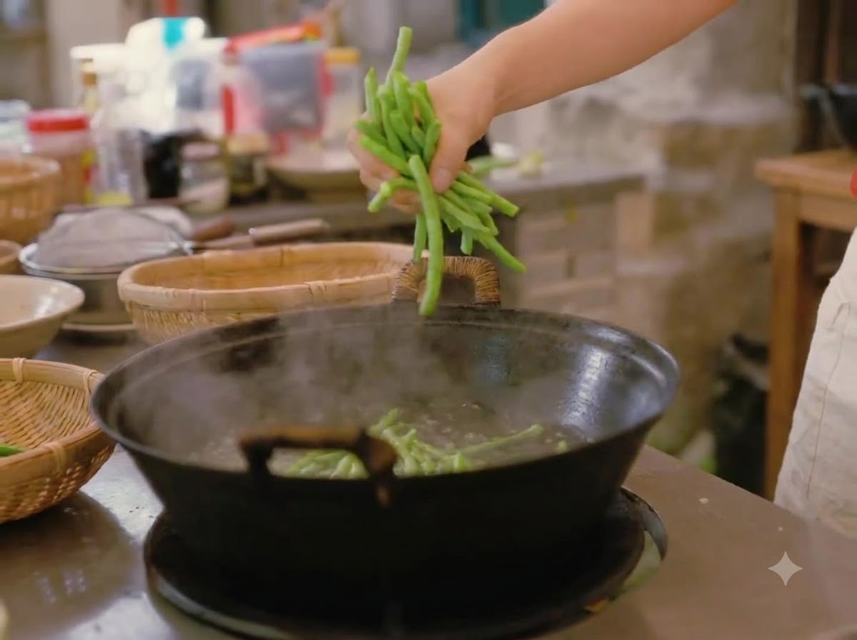 Eine Hand wirft frische grüne Bohnen in einen großen Wok mit kochendem Wasser.