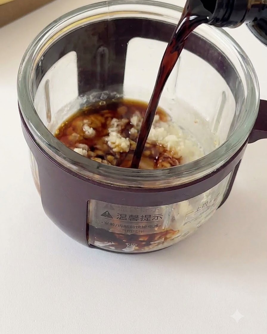 Dunkle Sojasauce wird aus einer Flasche in einen Glasbehälter mit gehacktem Knoblauch und Gewürzen gegossen.