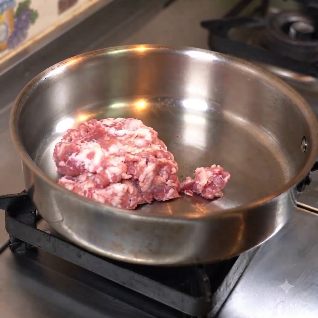 Hackfleisch wird zum Braten flach in eine Edelstahlpfanne gedrückt.