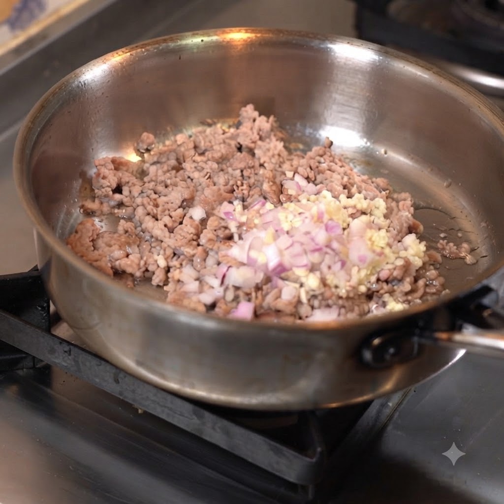 Hackfleisch wird in einer Pfanne mit gehacktem Knoblauch und Zwiebeln angebraten.