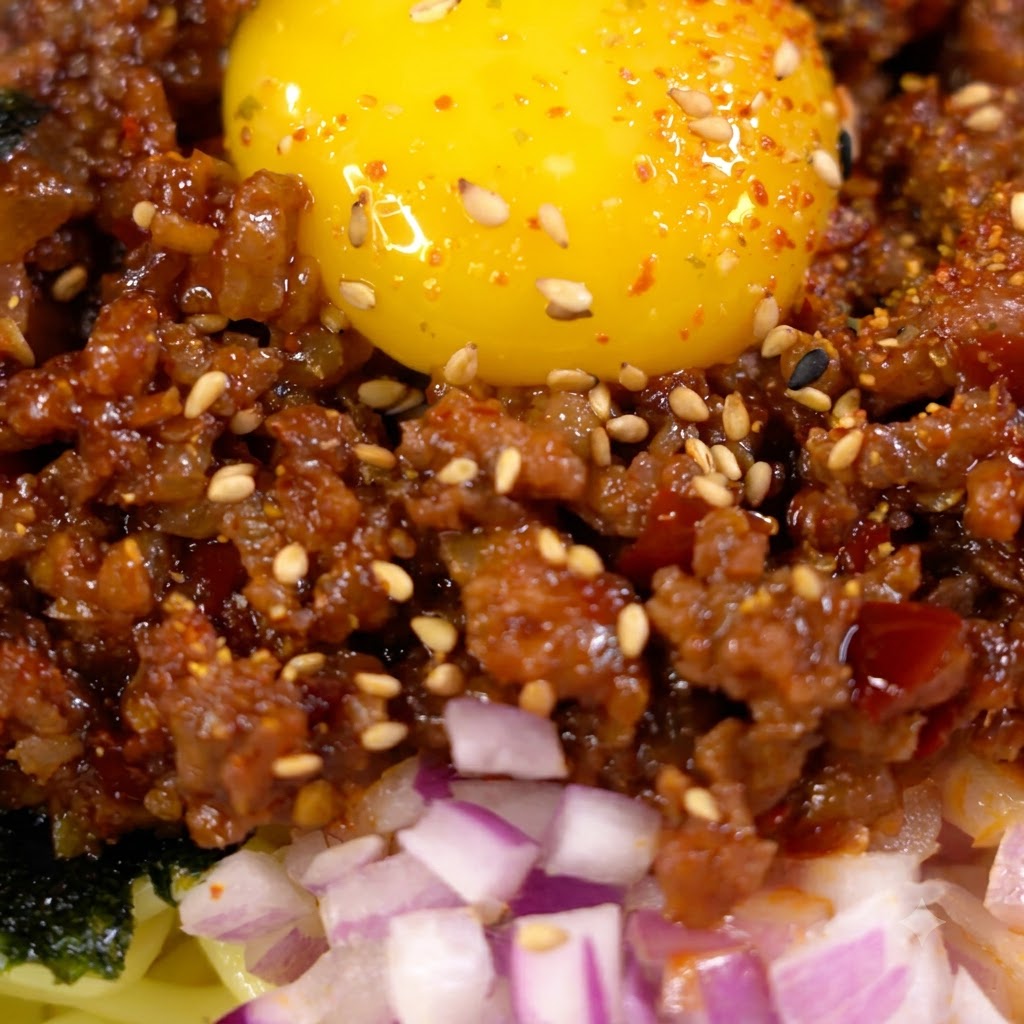Sauce wird in eine Pfanne mit gebräuntem Hackfleisch gegossen und verrührt.