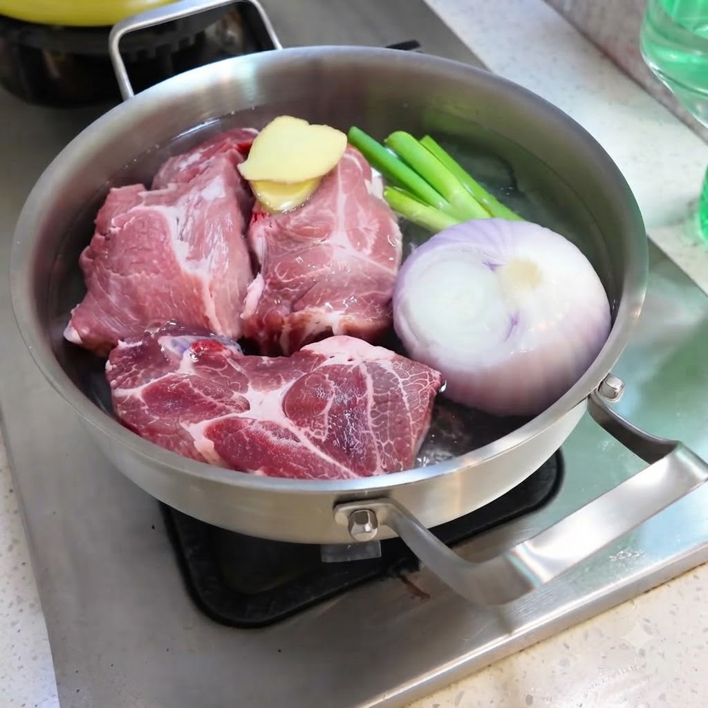 Wasser wird in eine Pfanne mit Schweinefleisch, Zwiebeln, Ingwer, Frühlingszwiebeln und Gewürzen gegossen.