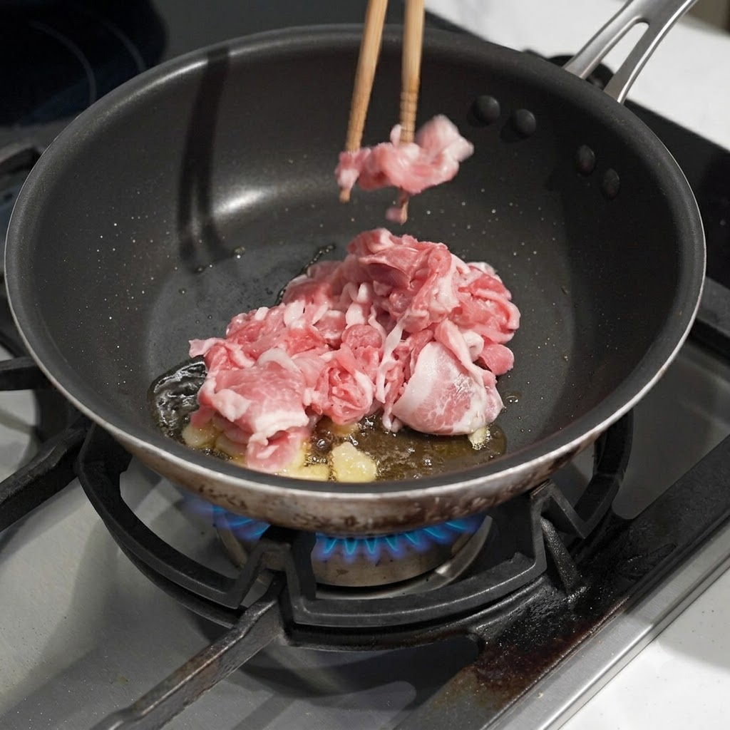 Rohes Schweinefleisch wird in eine Pfanne mit heißem Öl gegeben.