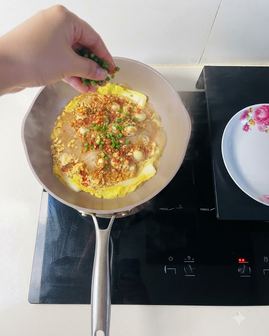 Frisch gehackte Frühlingszwiebeln werden über eine Pfanne mit gekochten Muscheln und Glasnudeln gestreut.