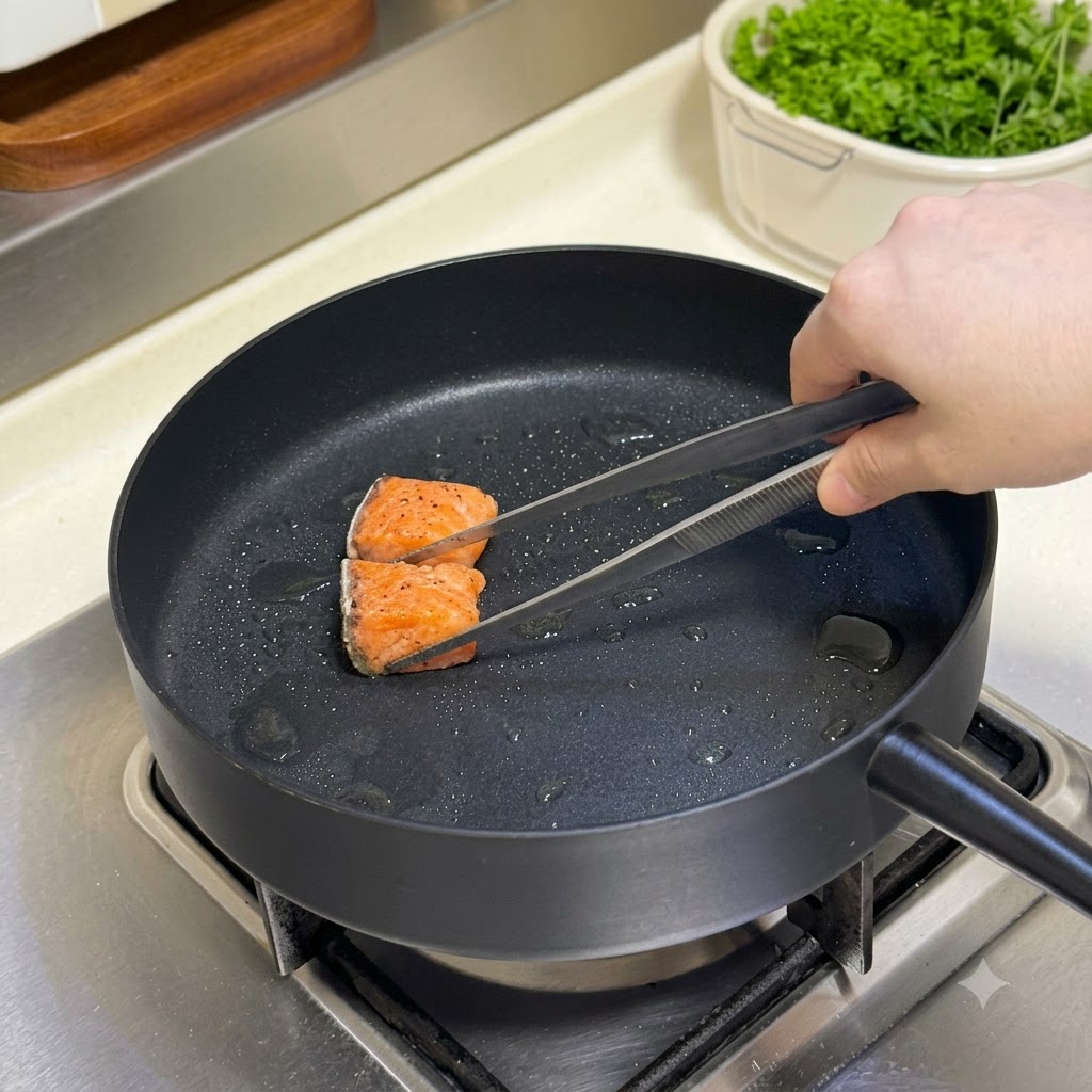 Gewürzte Lachs-Würfel werden mit einer Zange in einer heißen Bratpfanne gewendet.