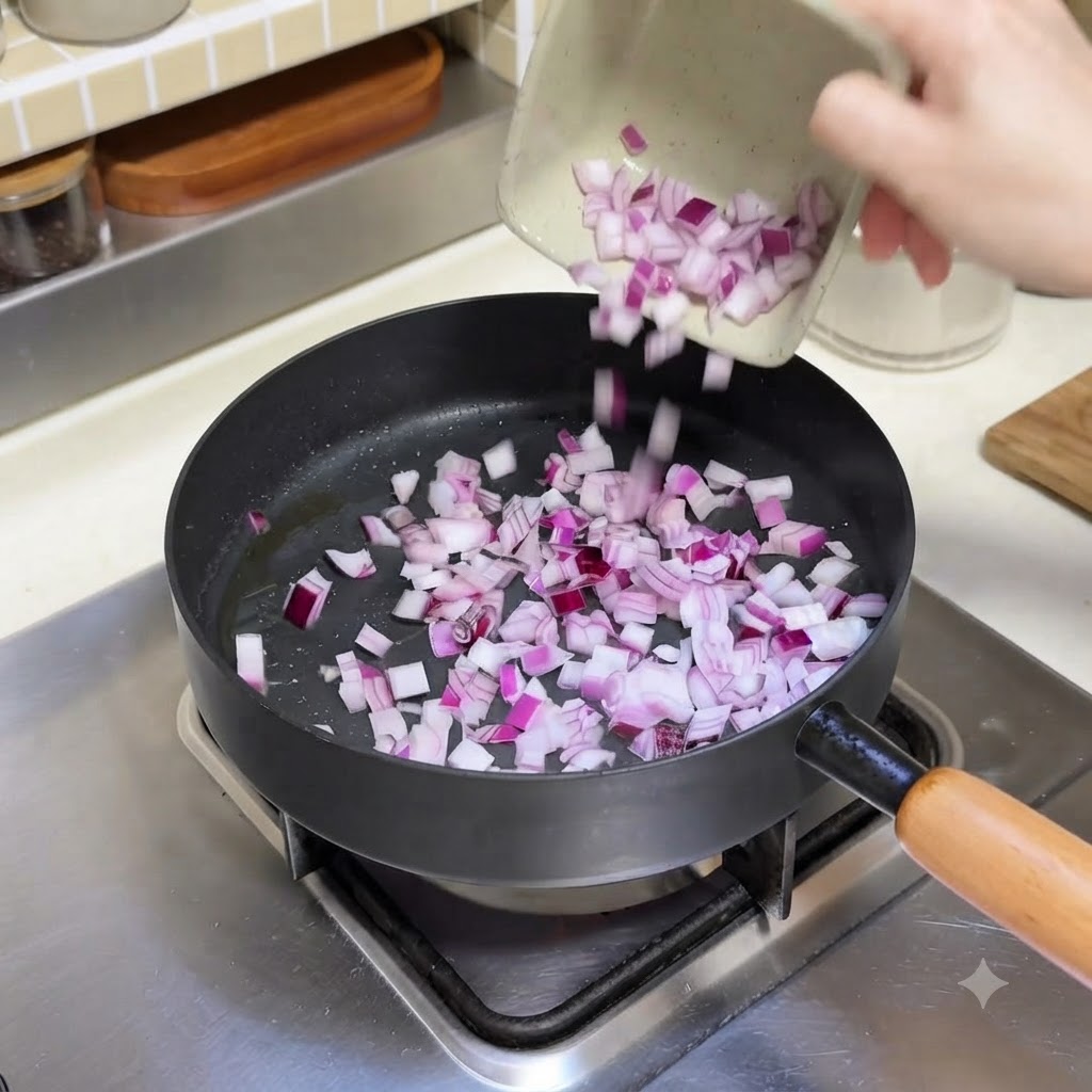 Gewürfelte rote Zwiebeln werden aus einer kleinen Schale in eine heiße Bratpfanne gegossen.