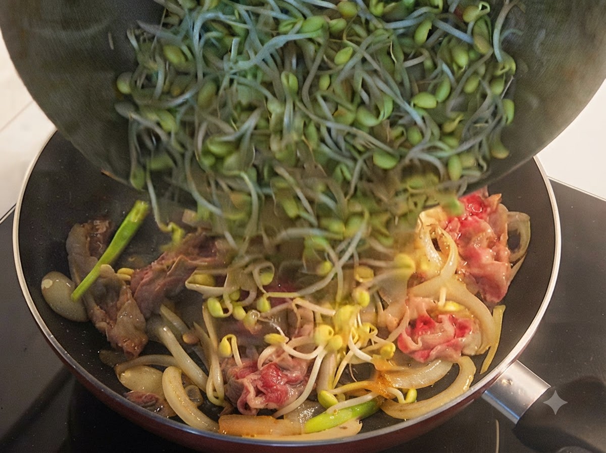 Frische gelbe Sojasprossen werden aus einer Schüssel in eine Bratpfanne mit halbgegartem Rindfleisch und Zwiebeln geschüttet.