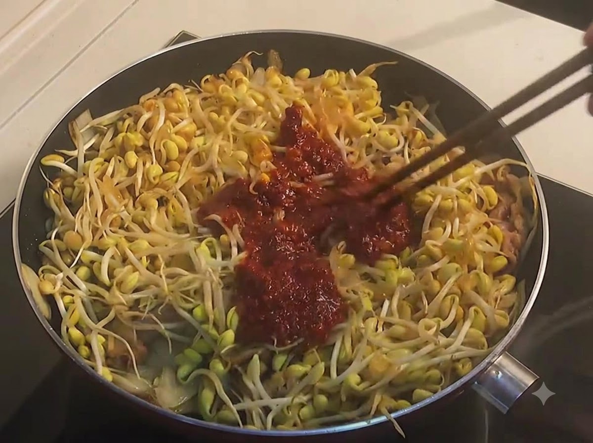 Stäbchen wenden gelbe Sojasprossen und Rindfleisch mit einer dicken, dunkelroten scharfen Sauce in einer Pfanne.