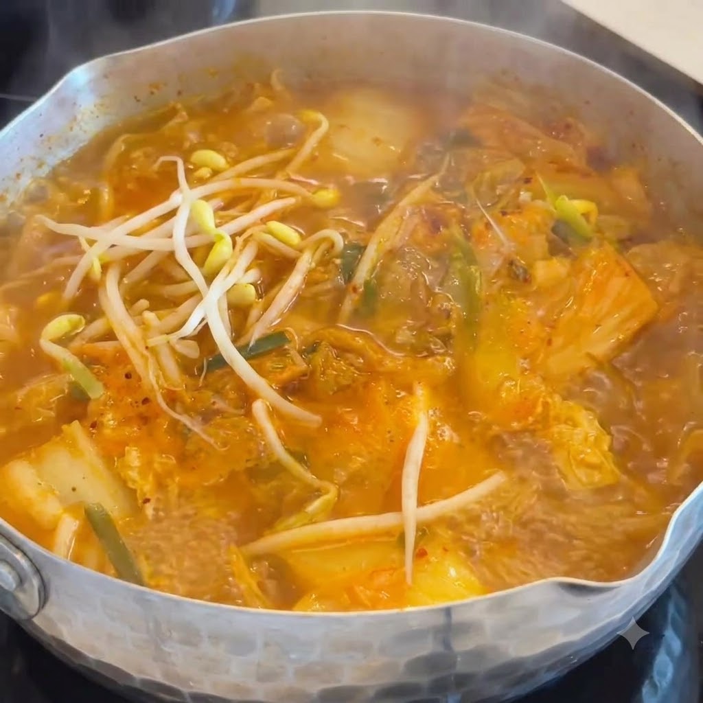 Knackige weiße Bohnenkeimlinge werden in einen köchelnden Topf mit orangefarbener Kimchi-Wurst-Suppe gegeben.