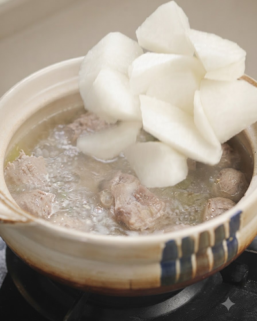 Weiße Rettichstücke werden in einen Topf mit blubbernder Suppe gegeben.