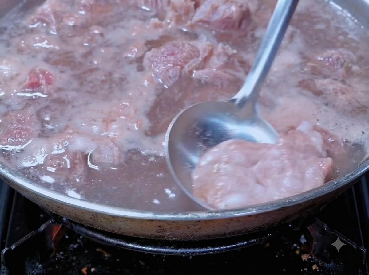 Eine Schöpfkelle entfernt Blutschaum von kochendem Rindfleisch in einem Kochtopf.