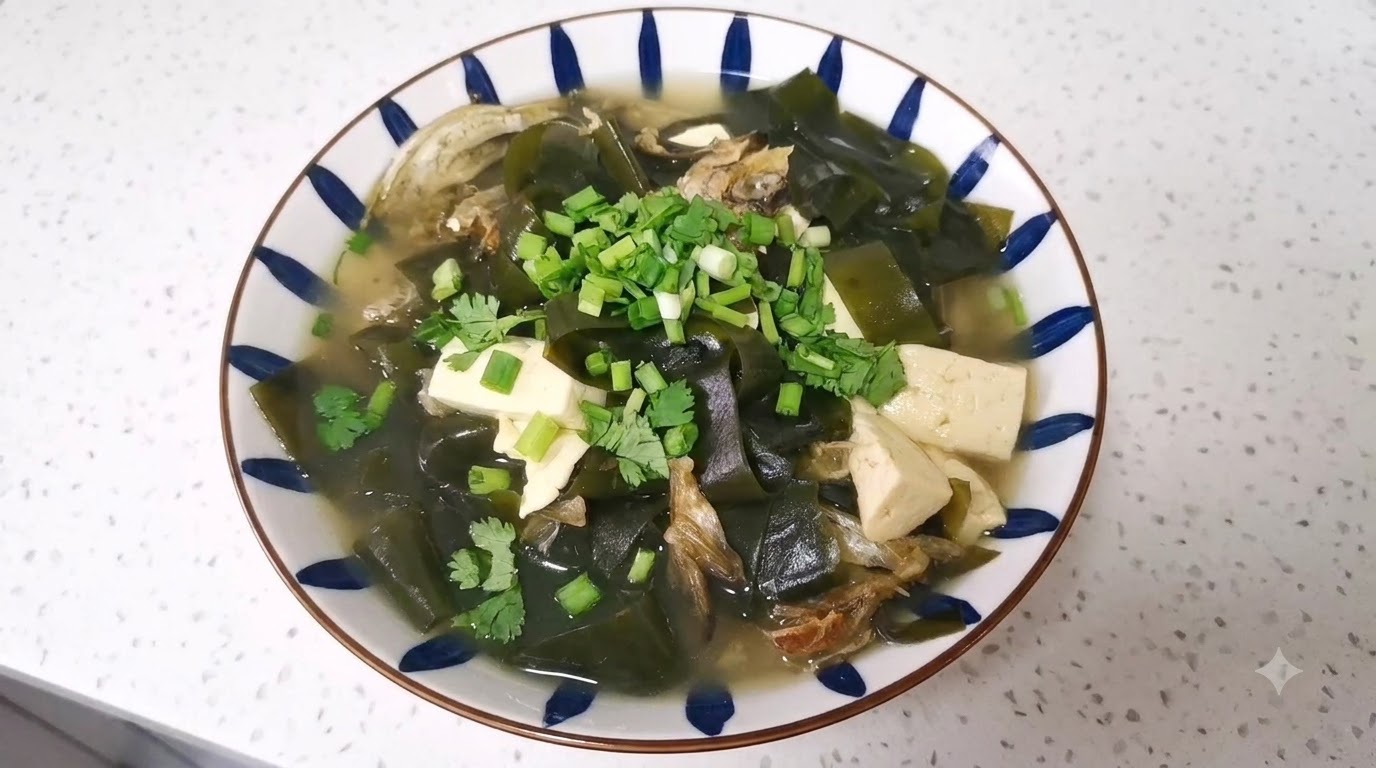 Eine Schüssel mit getrockneter Pollack-Tofu-Suppe und Algen, garniert mit Frühlingszwiebeln und Koriander in einer weiß-blauen Schale.