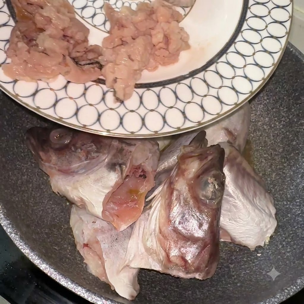 Alaska-Seelachsstücke und -köpfe werden von einem gemusterten Teller in eine Pfanne gegeben.
