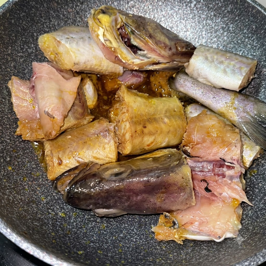 Seelachsstücke braten zusammen mit in Scheiben geschnittenen gelben Kartoffeln in der Pfanne an.