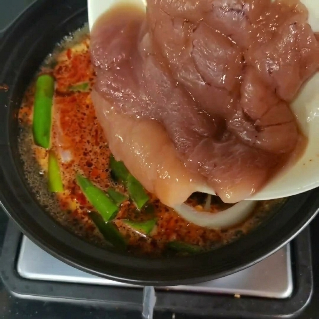 Frische Stücke vom Pollackrogen werden von einem Teller in die köchelnde Suppe mit grünem Gemüse geschoben.