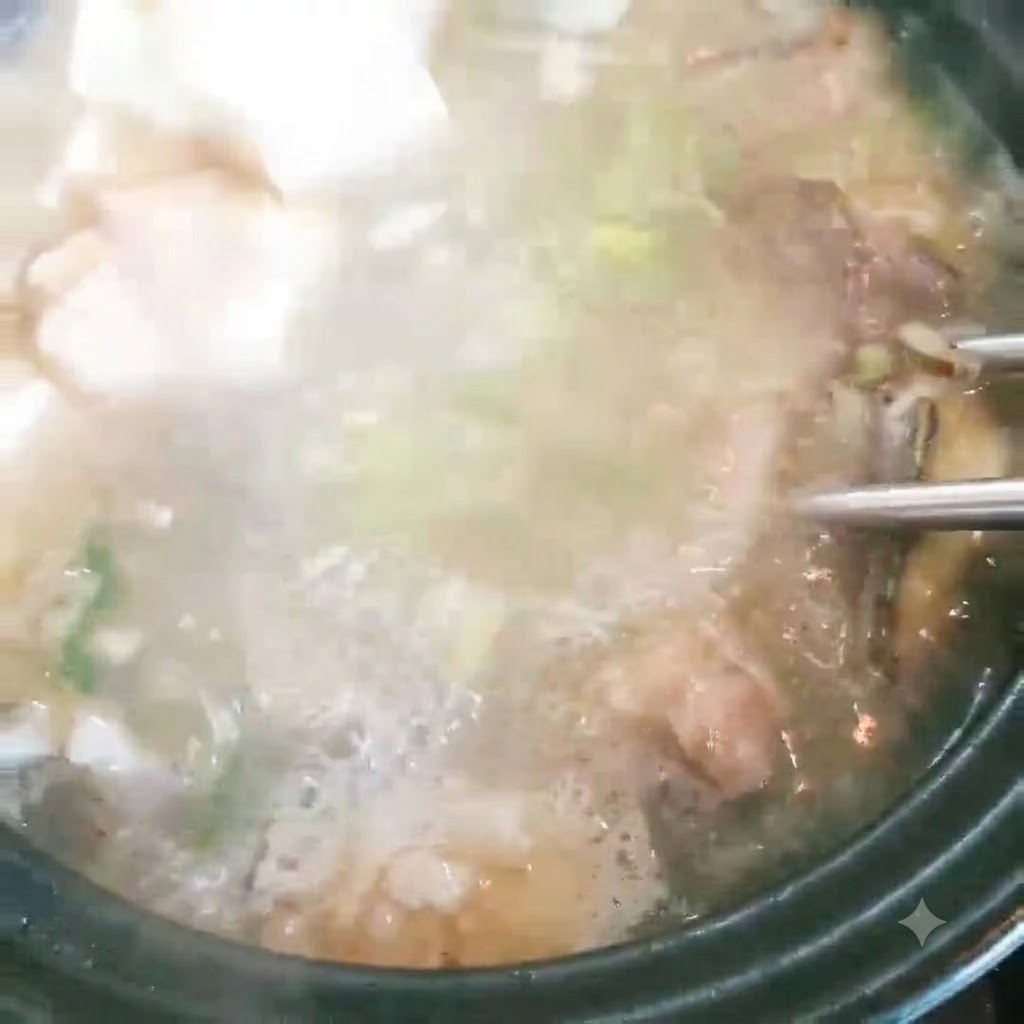 Tofuwürfel werden in einen Topf mit blubbernder Fischsuppe und Frühlingszwiebeln gegeben.