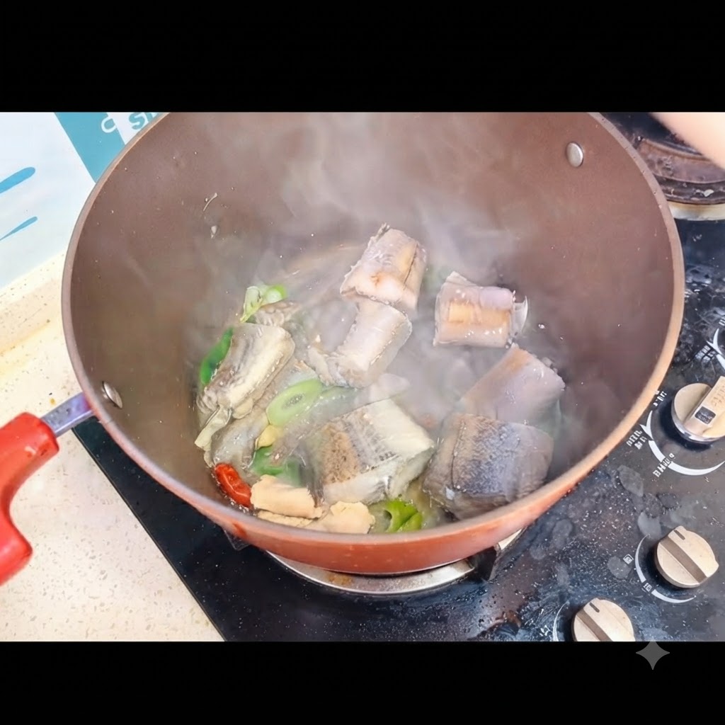 Kochendes Wasser wird über die Fischstücke in einem Kochtopf auf dem Herd gegossen.
