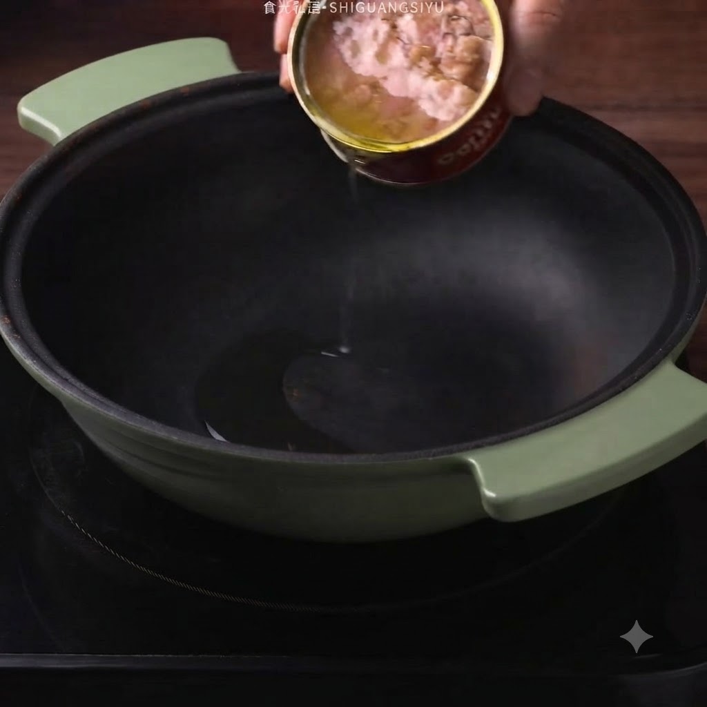 Thunfisch-Dosenöl wird aus einer Dose in einen dunkelgrünen Topf gegossen.