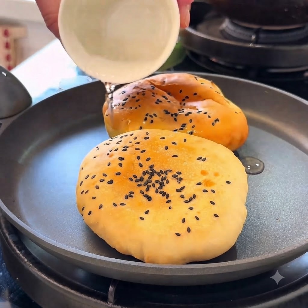 Burgerbrötchen werden in einer Pfanne mit Wasser unter einem Deckel erwärmt.