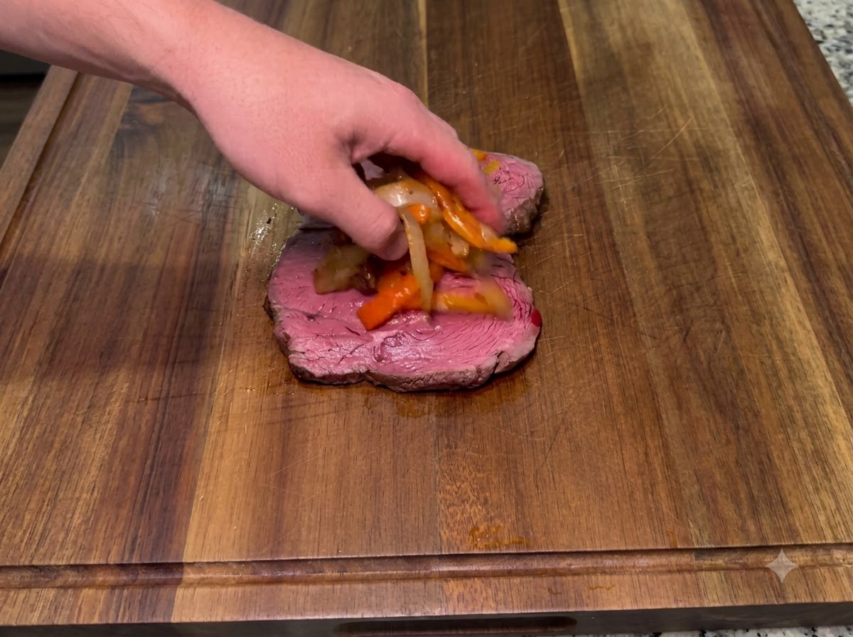 Geschmorte Zwiebeln und geräucherte scharfe Paprikaschoten werden auf ein unteres Steakstück gelegt.