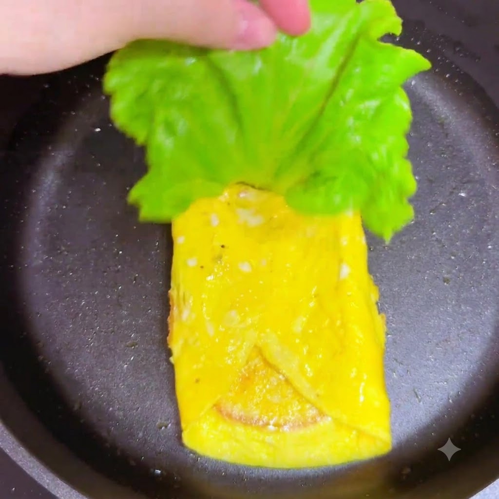 Ein frisches grünes Salatblatt wird in der Pfanne über die Schinkenschicht gelegt.