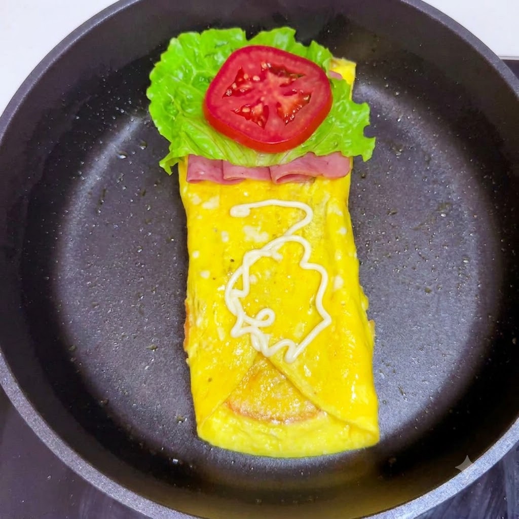 Weiße Salatsauce wird spiralförmig auf die Tomatenscheibe geträufelt.