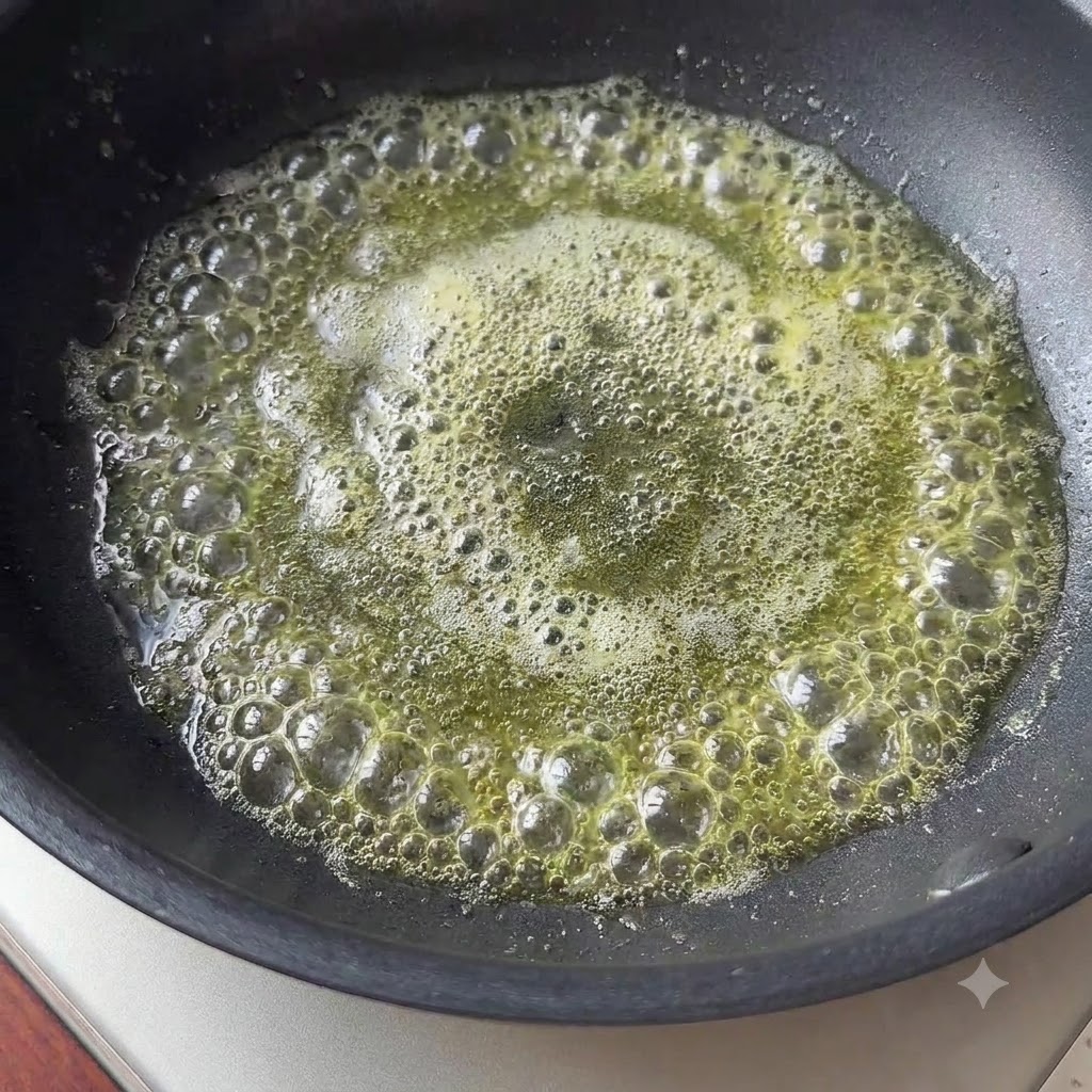Ein kleines Stück Butter schmelzt und wirft Blasen in einer schwarzen Pfanne.