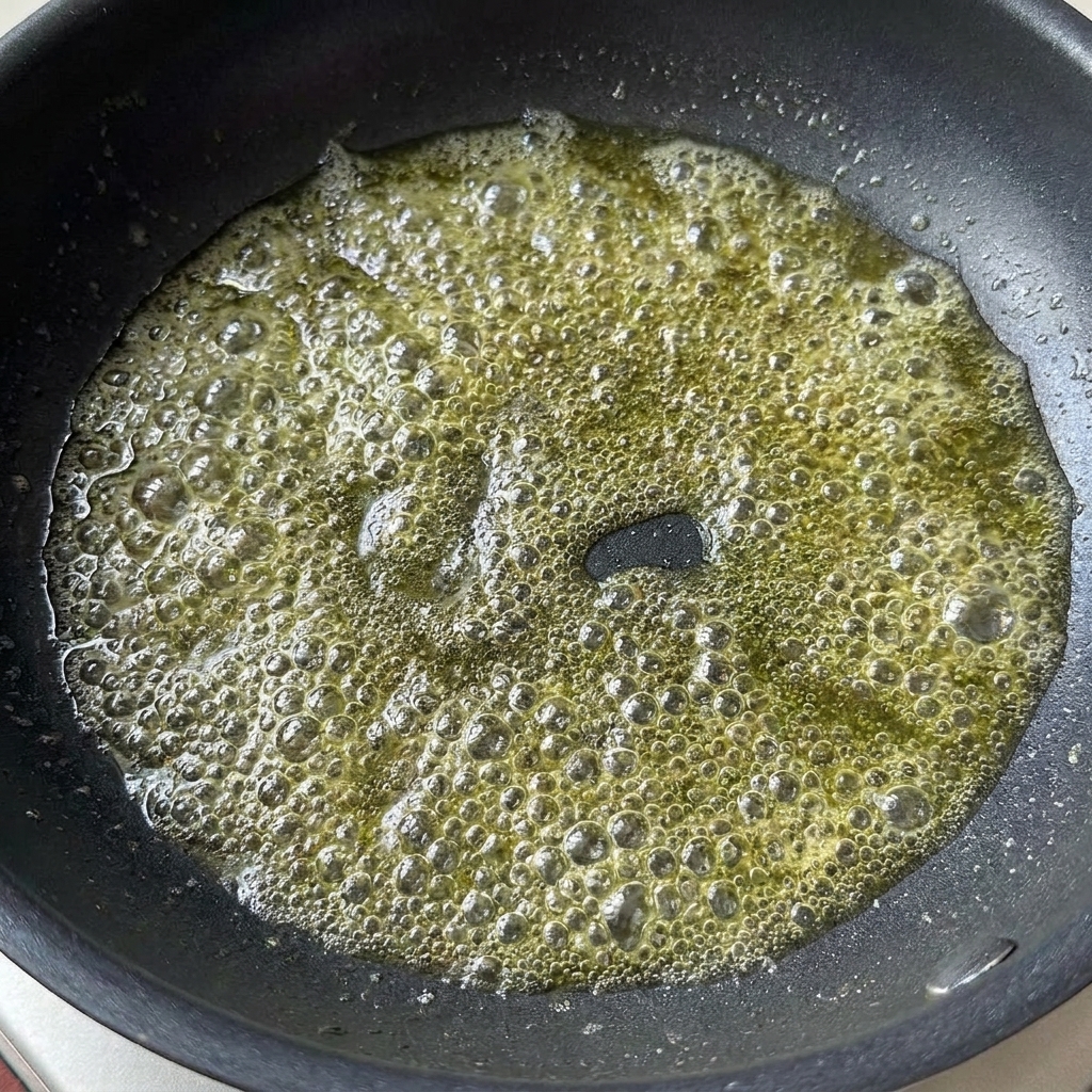 Helle Sojasoße und Tomatenmark werden zu geschmolzener Butter in eine Pfanne gegeben.