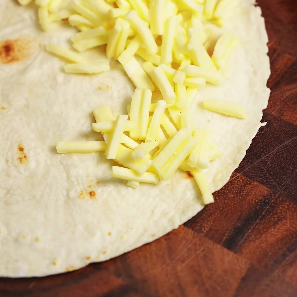 Gekochte Rindfleischfüllung und Mozzarella-Käse werden auf einer Hälfte einer flachen Weizentortilla angerichtet.