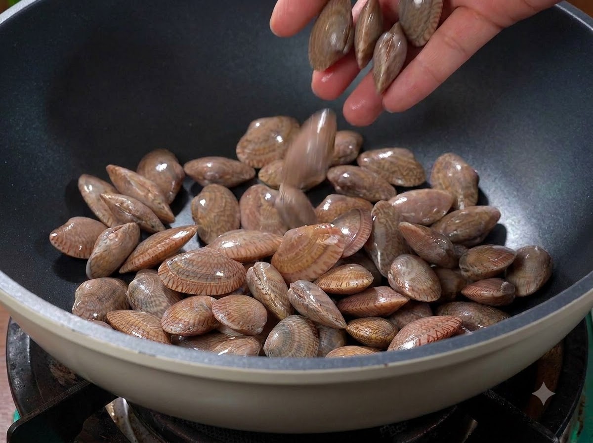 Muscheln werden in einen heißen, trockenen Wok auf dem Herd gegeben.