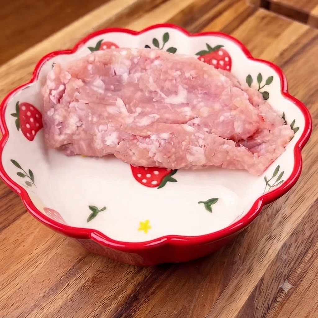 Hackfleisch in einer gemusterten Schüssel mit gehackten Frühlingszwiebeln oben drauf.
