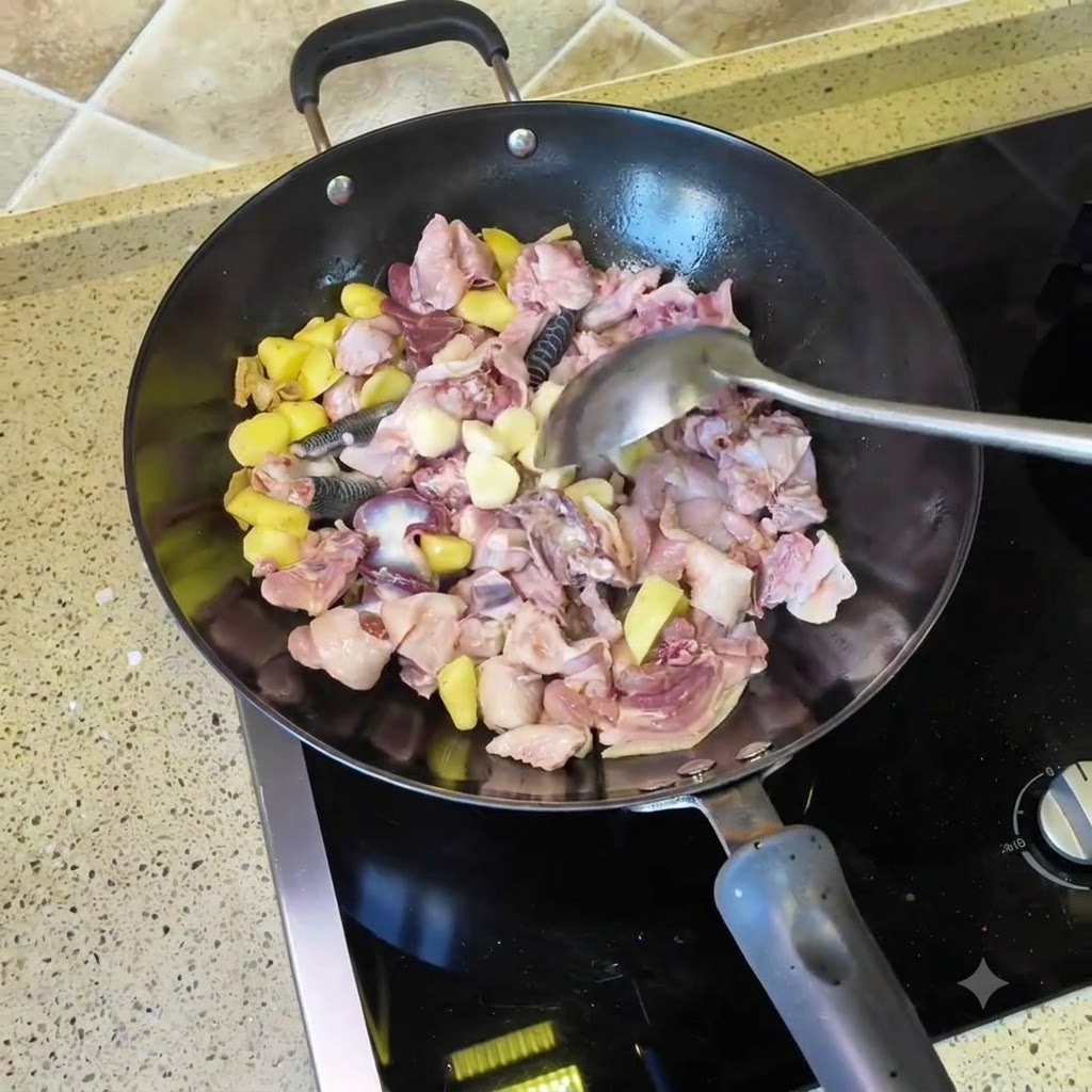Knoblauchzehen und getrocknete Chilischoten werden in den Wok mit Hähnchen- und Ingwerstücken gegeben.