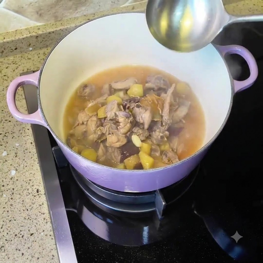 Hähnchen und Suppe köcheln in einem lila Dutch Oven auf dem Herd mit einer Schöpfkelle in der Nähe.