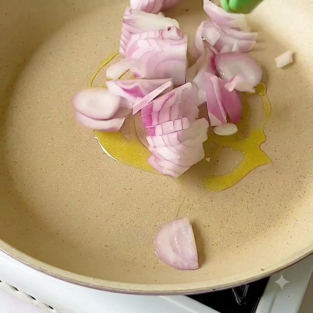 Geschnittene rote Zwiebeln brutzeln in Olivenöl in einer Pfanne.